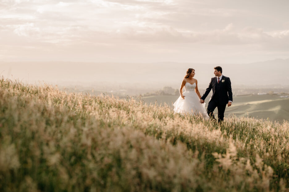 wedding photos walking in field of high grass at Eagle Ridge New Zealand