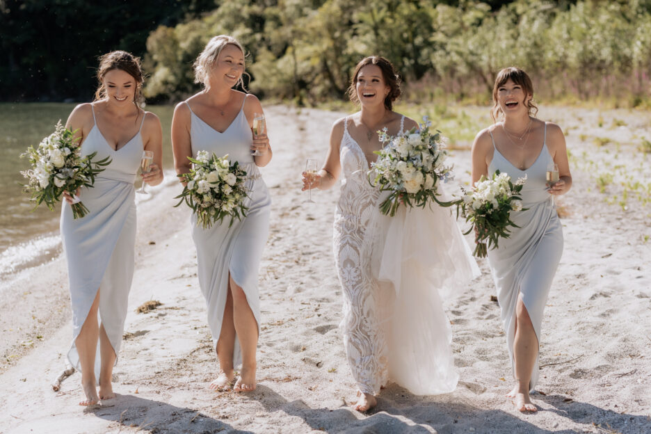 Bride with bridesmaids in pistachio green dresses walking laughing at Lake Okataina Rotorua