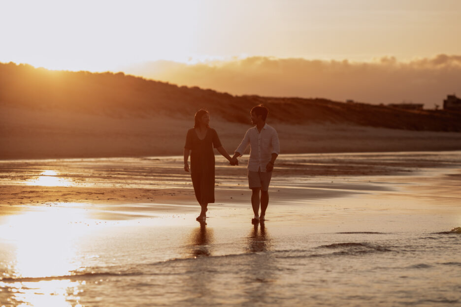 couple walking beach engagement photos sunset