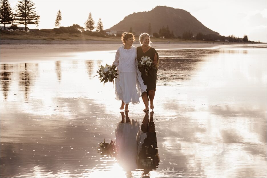 Sisters happily walking as bride and bridesmaid in sage green dress
