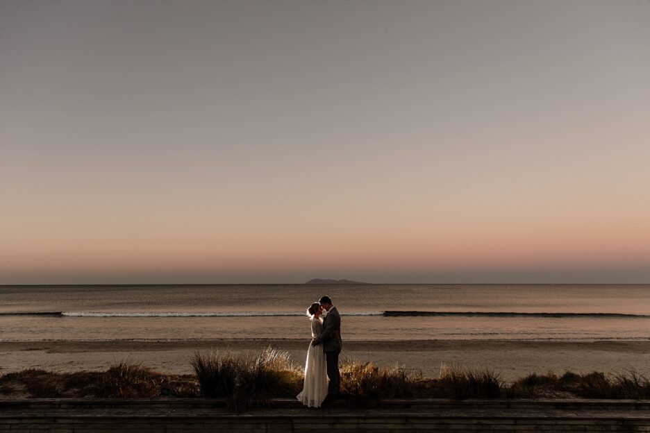 Waihi Beach sunset with wedding couple in front of beach