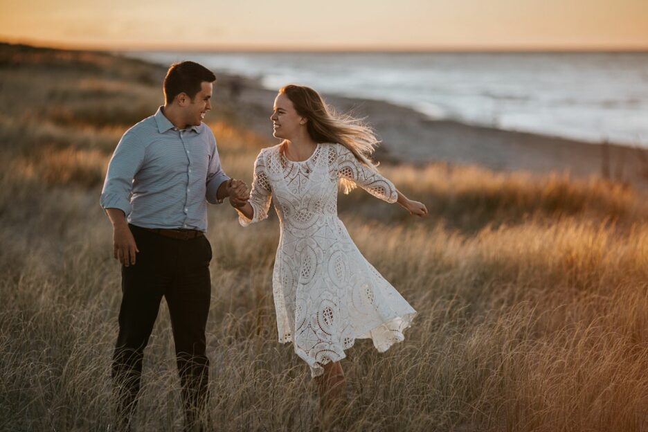 happy running couple on the beach at Whakatane in golden light