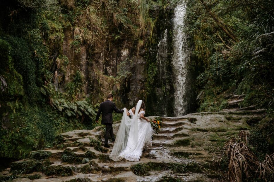 Bride and Groom climbing rocks at Kaiate Falls New Zealand