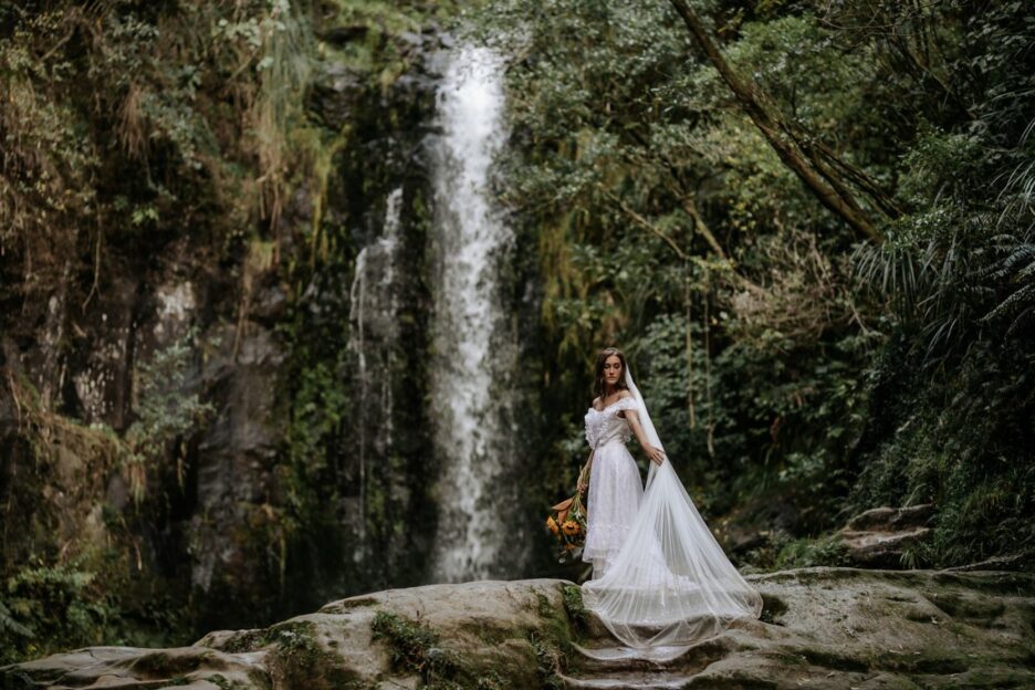 Bride in vintage dress by waterfall
