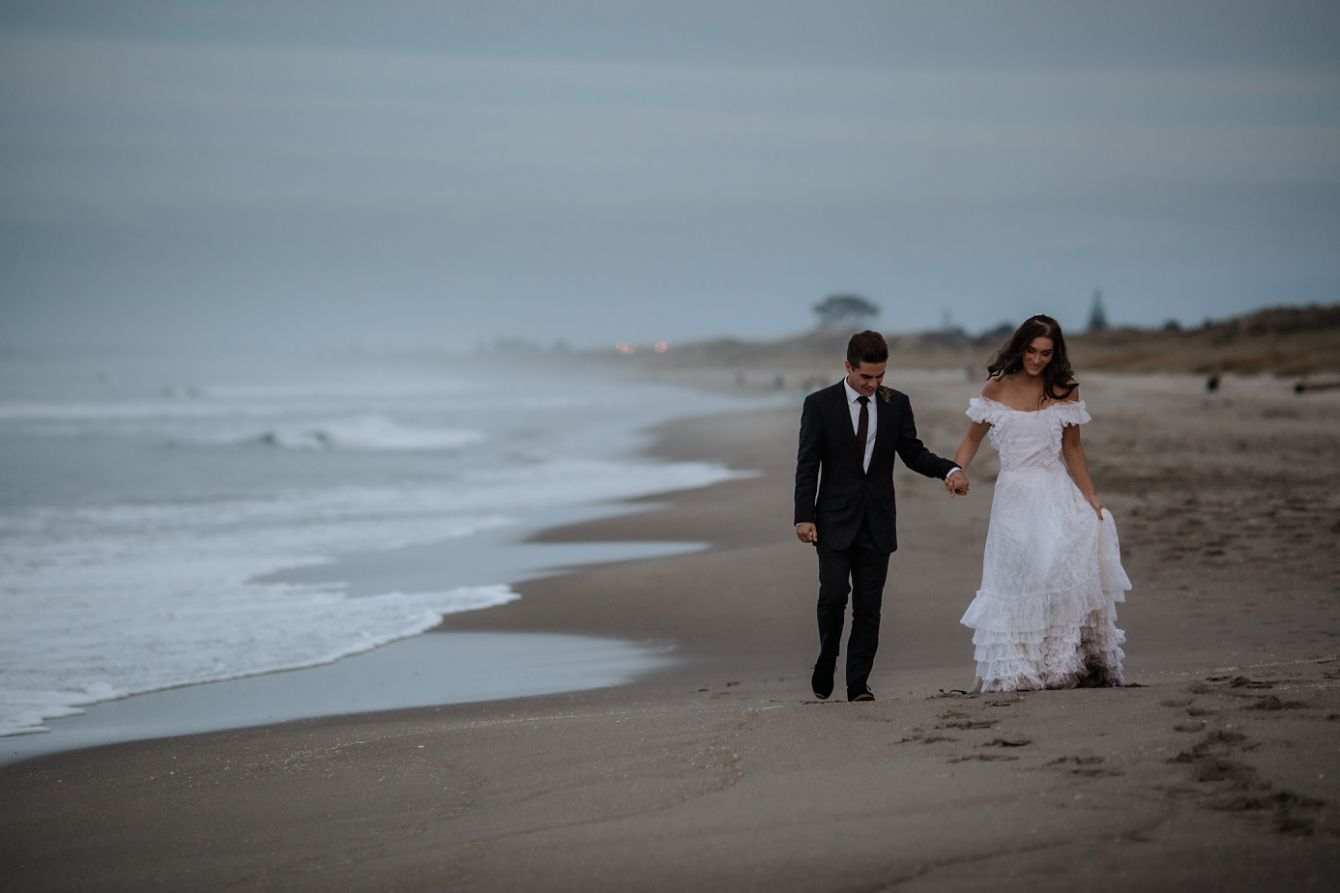 Bride and groom walking on Papamoa Beach at Winter time