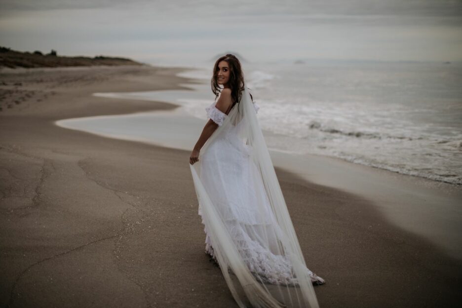 Happy natural bride walking on the beach dress dragging in the sand