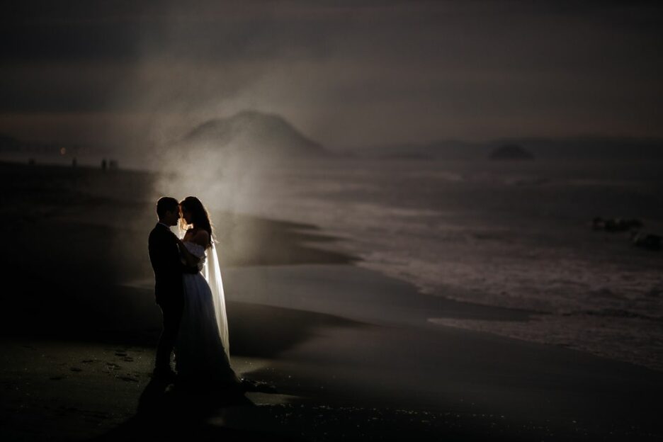 Elopement wedding waters edge beach photo lit up