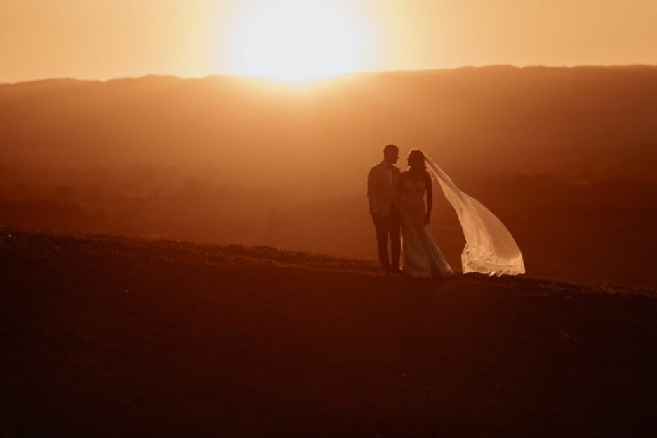 Golden hour sunset photo with bride and groom walking on the hills
