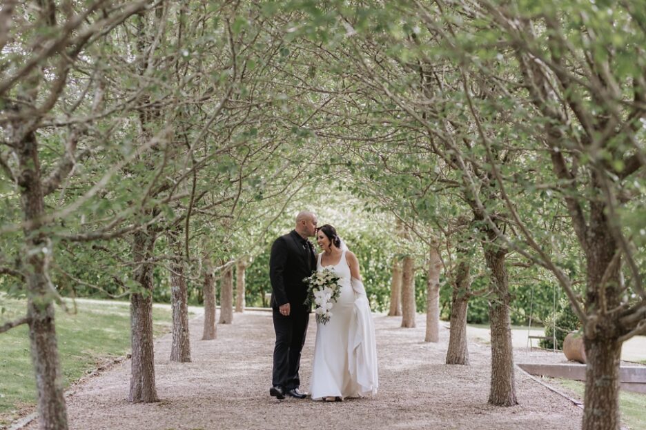 Groom kisses bride at Ataahua pear tree aisle