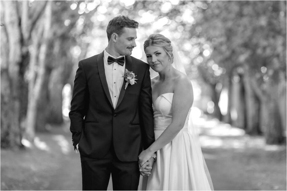 Groom looks at Bride in Black and white on driveway