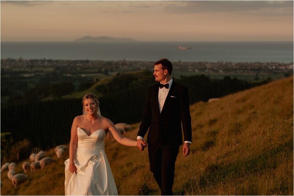 Natural happy wedding photos of couple walking towards camera over the hills of Welcome Bay