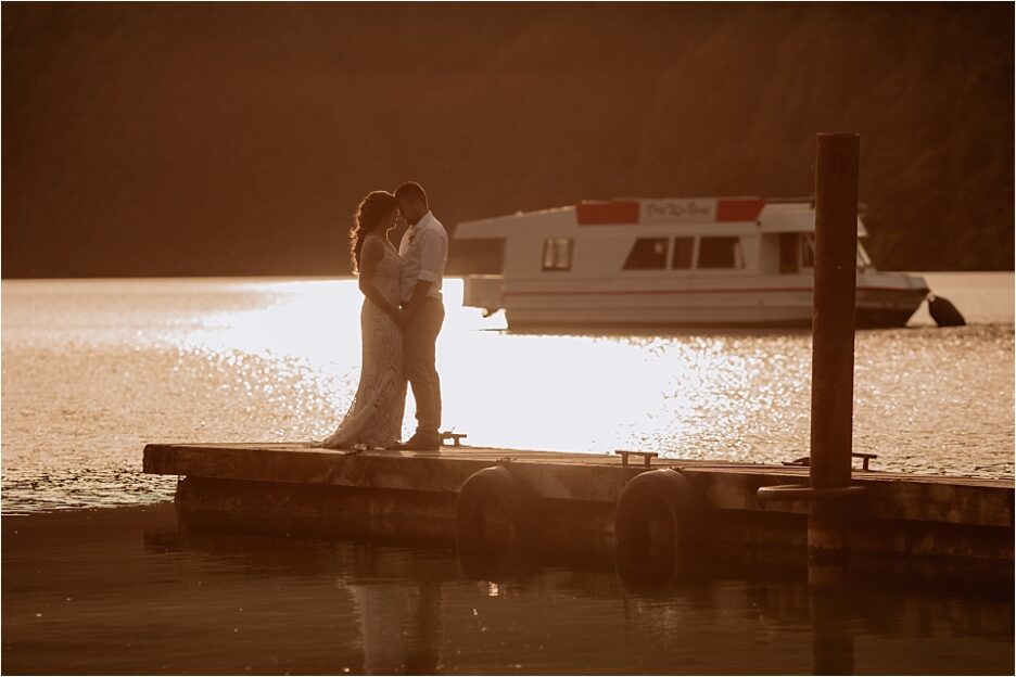 wedding photos on the pier at Lake Okataina with that 70's boat behind them