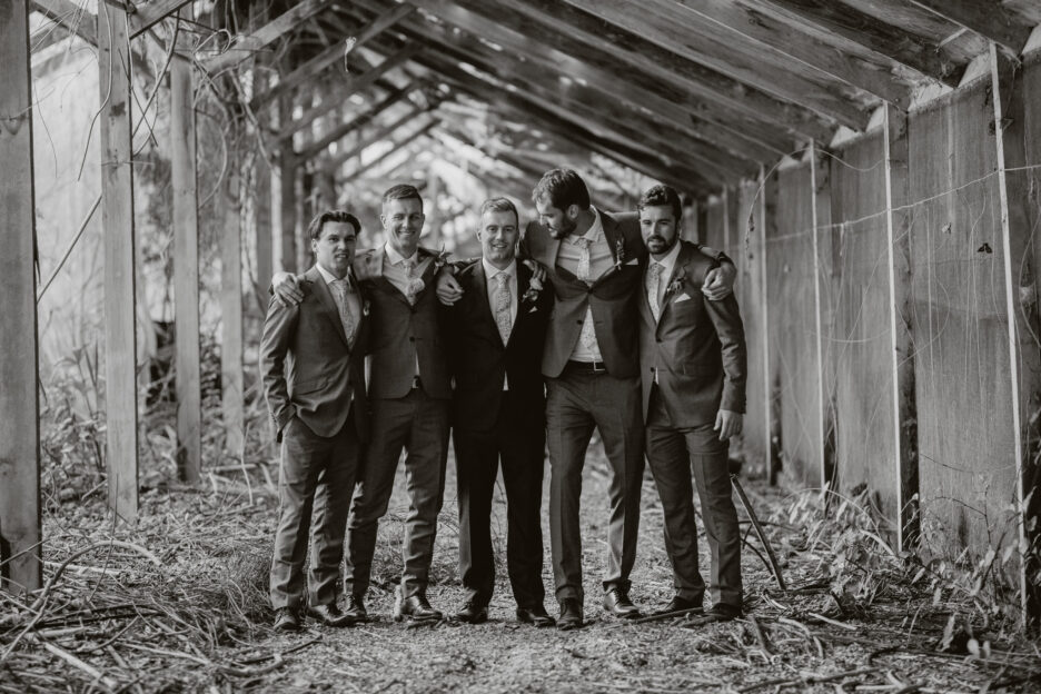 Black and white photo of groomsmen hugging in abandoned building