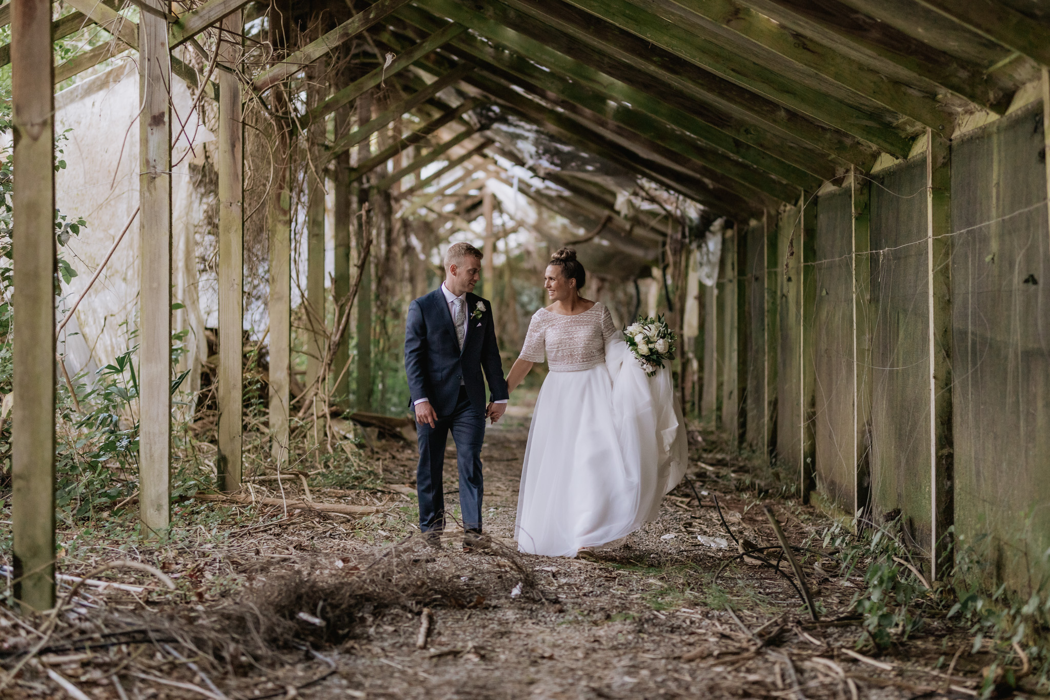 Happy wedding couple walking in rustic abandoned glass house