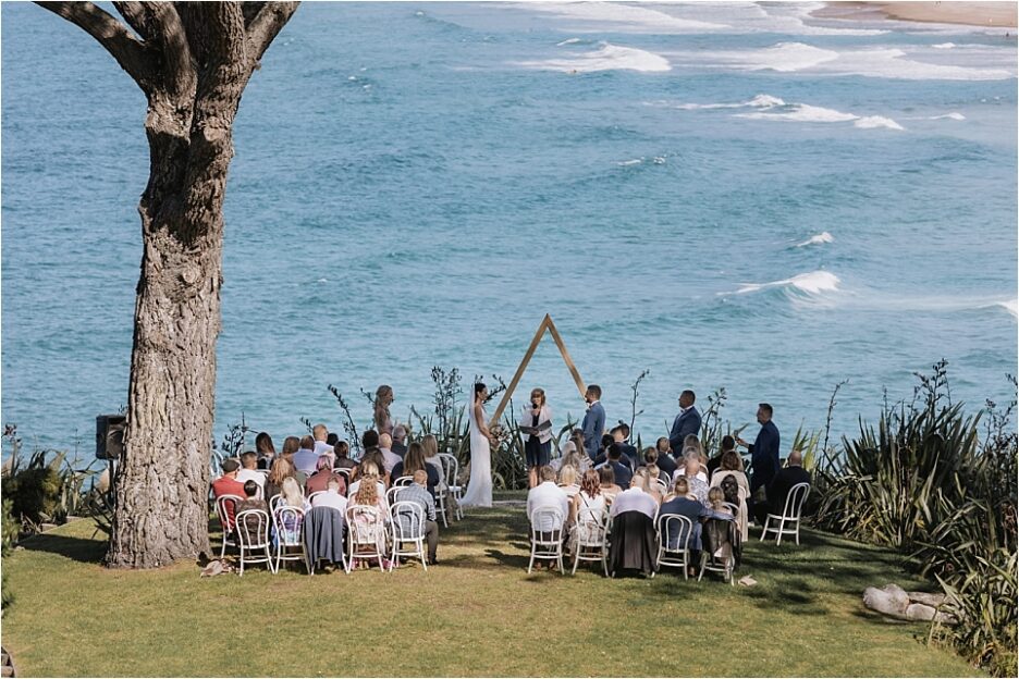 Scene of wedding ceremony in progress overlooking ocean at Orua Beach house