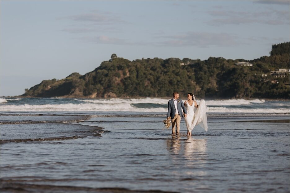 Bride and groom walking in ocean at Hot Water beach
