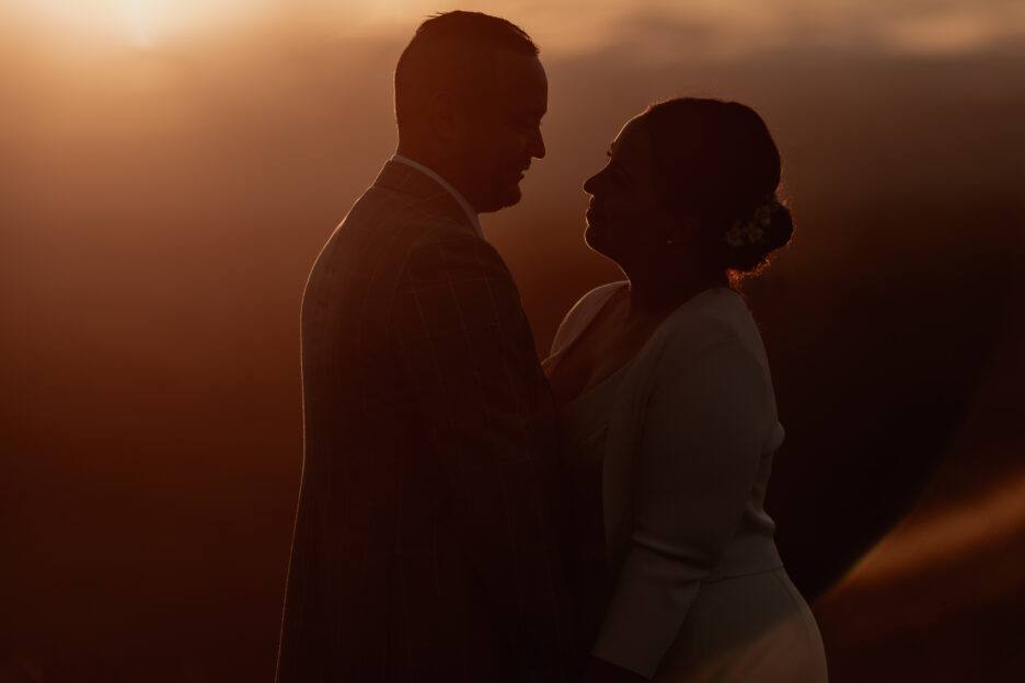 Couple looking at each other in moody wedding image at golden light