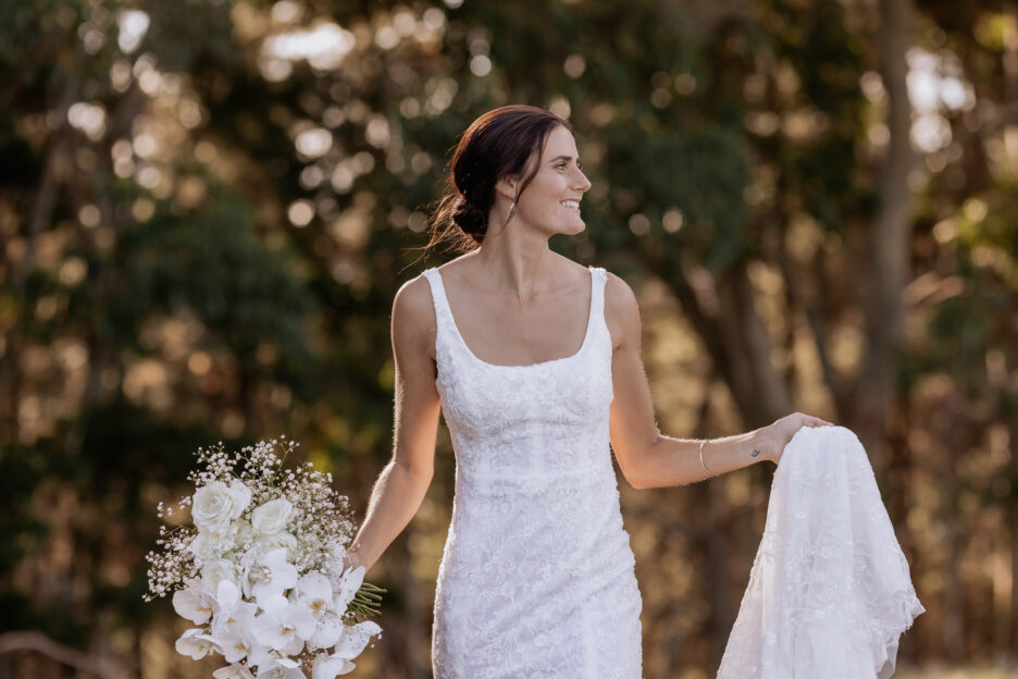 Country bride in lace dress walking holding veil