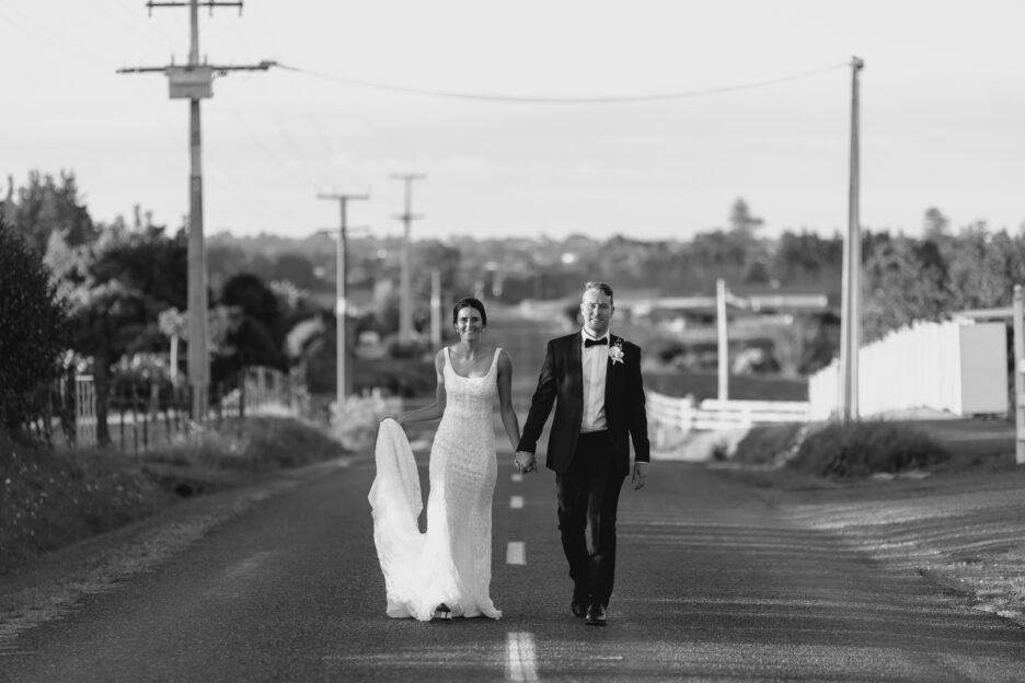 Bride and groom walking up country road in black and white