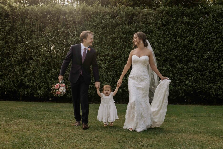 Bride and groom walking holding hands with flower girl