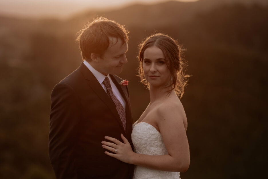 beautiful bride stares at camera with her husband looking at her