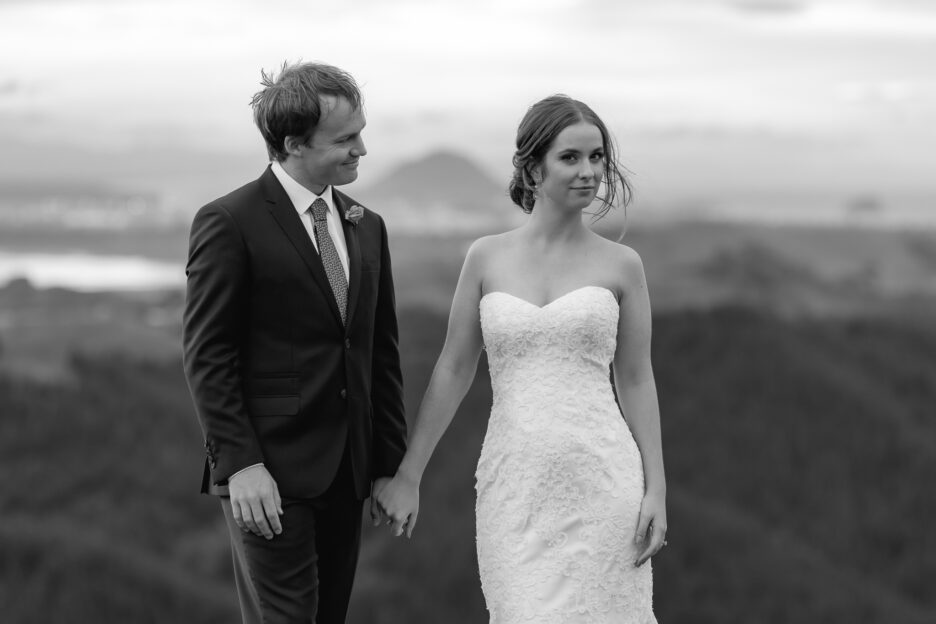 Cheeky natural bride with her husband with Mount Maunganui in New Zealand behind them