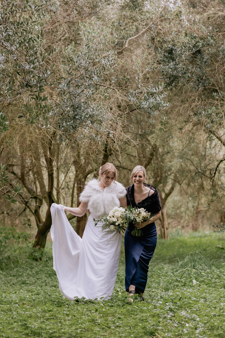 bride and bridesmaid in Olive grove at Bracu laughing