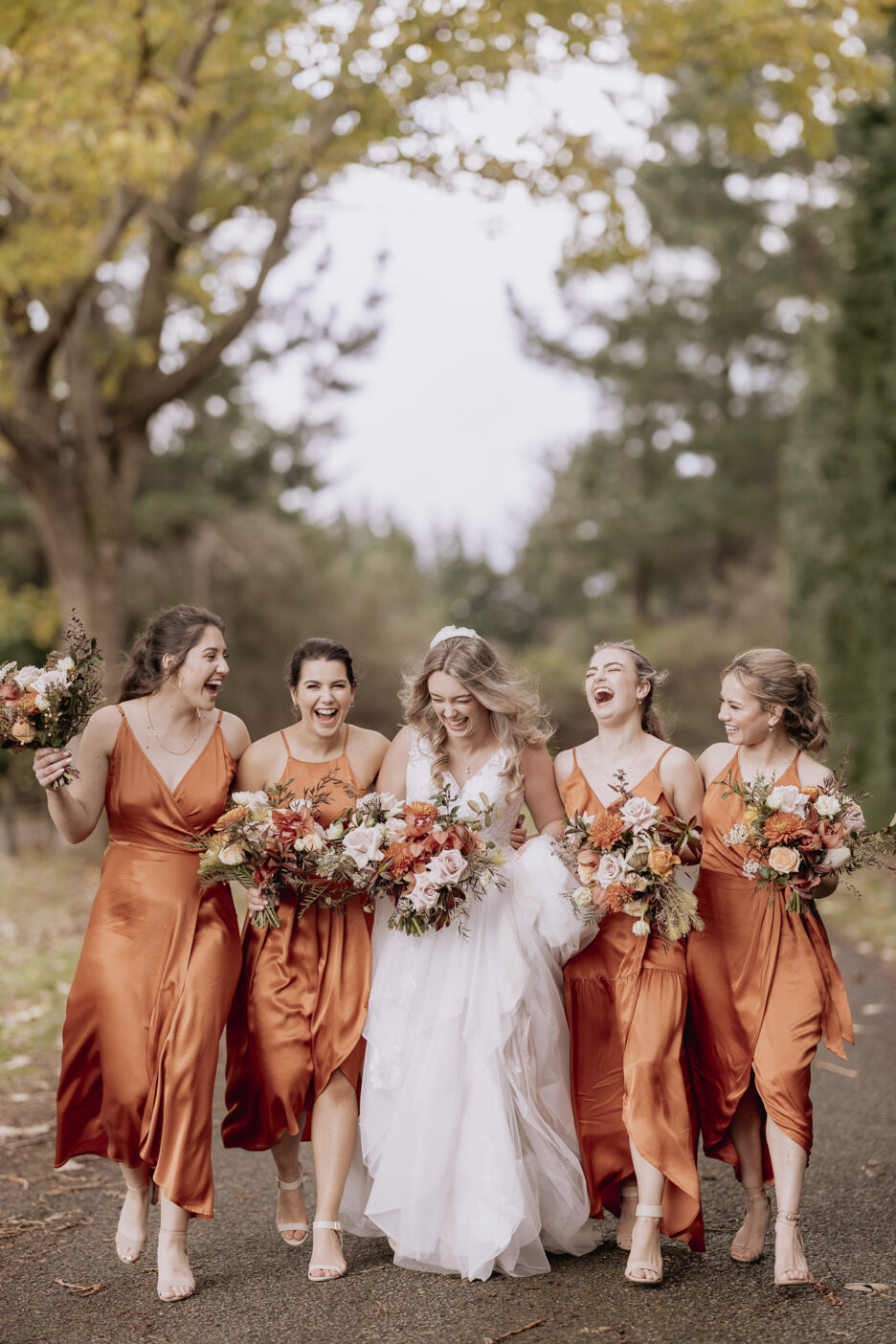 laughing happy bride with bridal squad girls in rust dresses