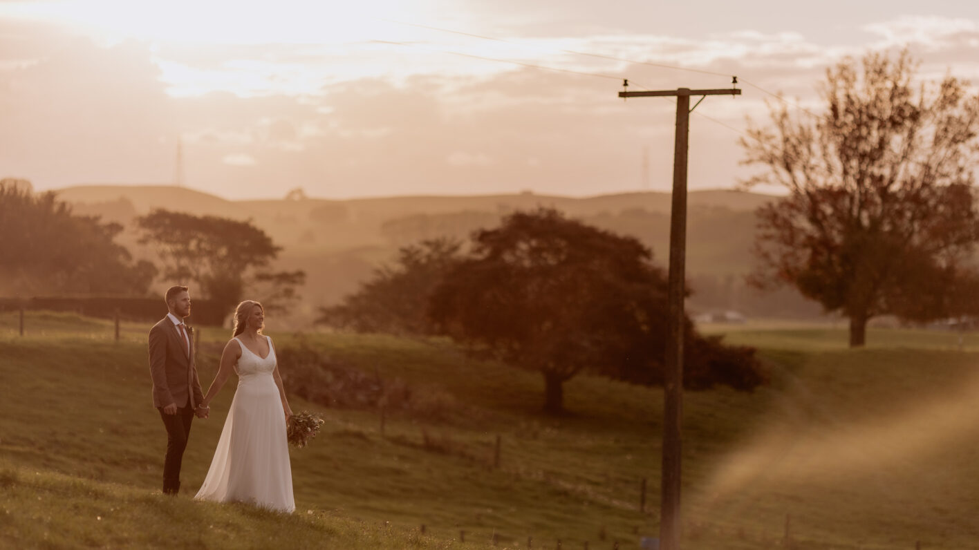 Bride and groom looking at kaimais country setting at sunset