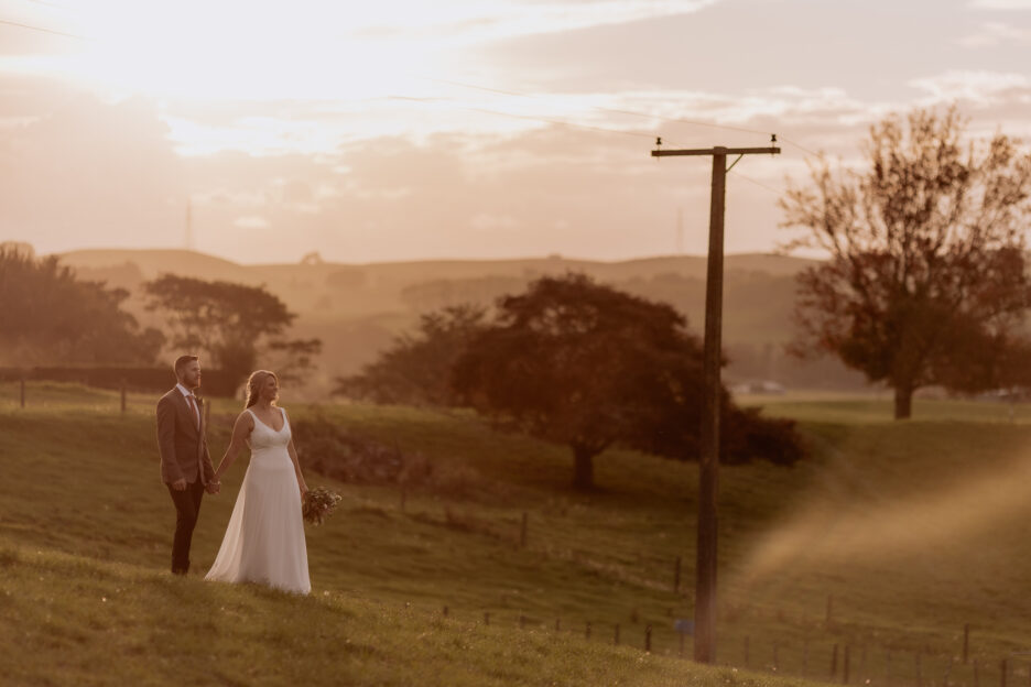 Bride and groom looking at kaimais country setting at sunset