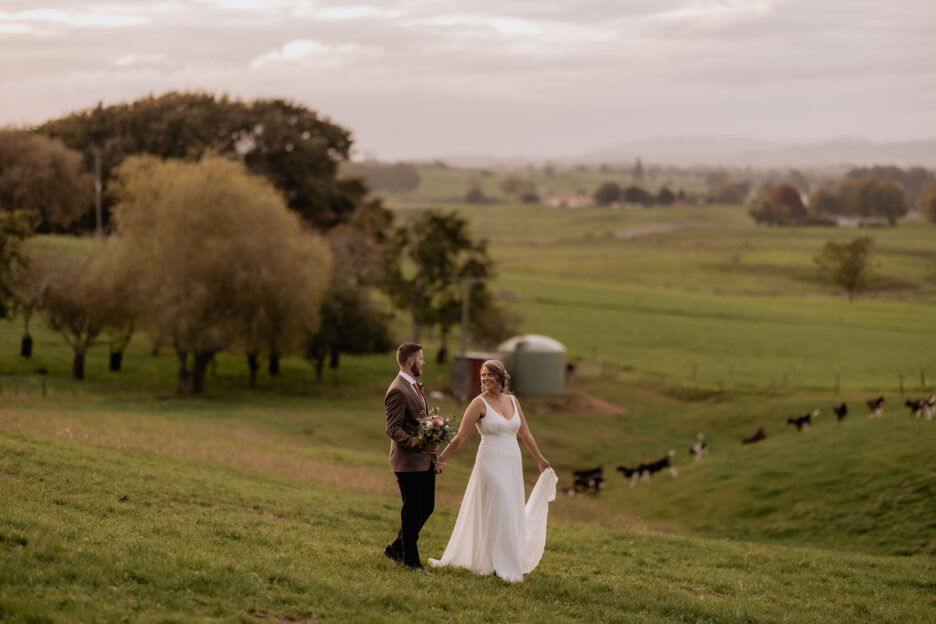Bride and groom walking over farm in the waikato