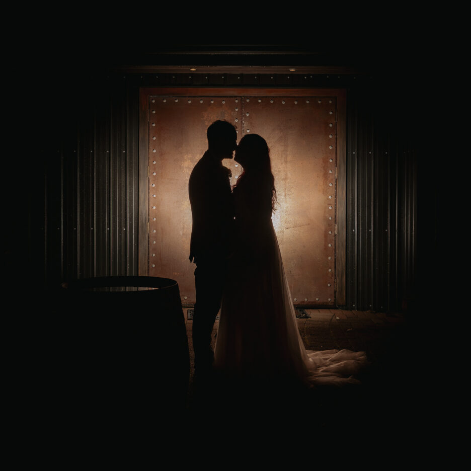 Bride and groom kissing in front of copper doors at Eagle Ridge estate