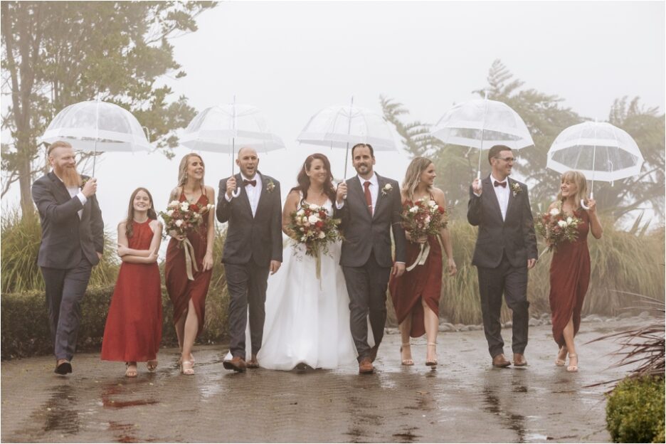Bridal party walking in the rain with umbrellas
