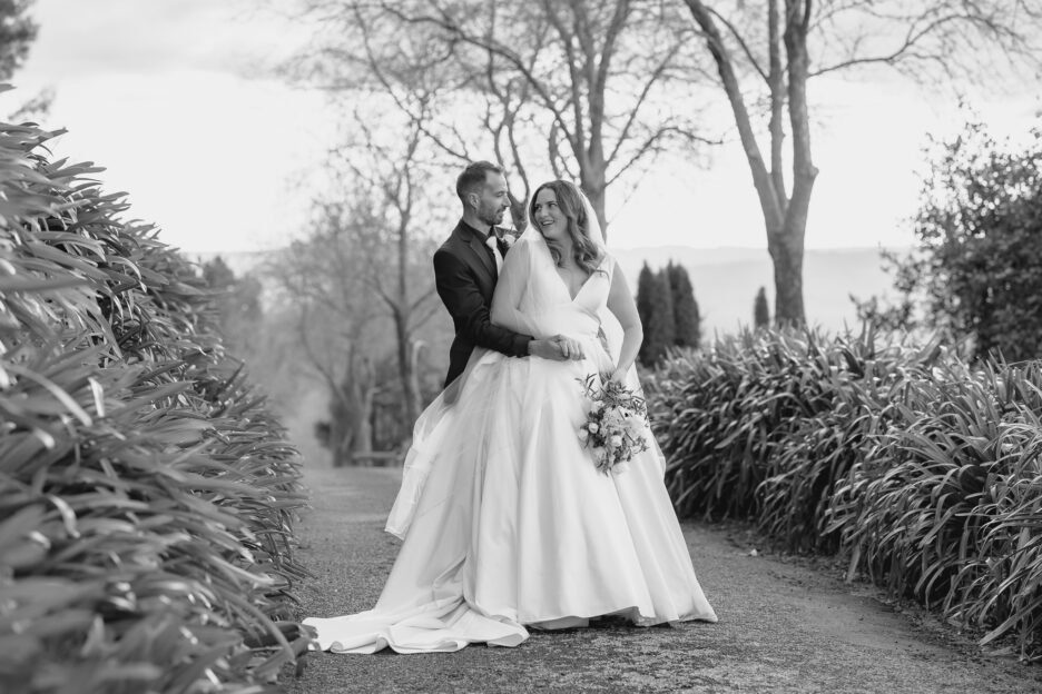 natural unposed smiling wedding photo in black and white bride looks back at groom