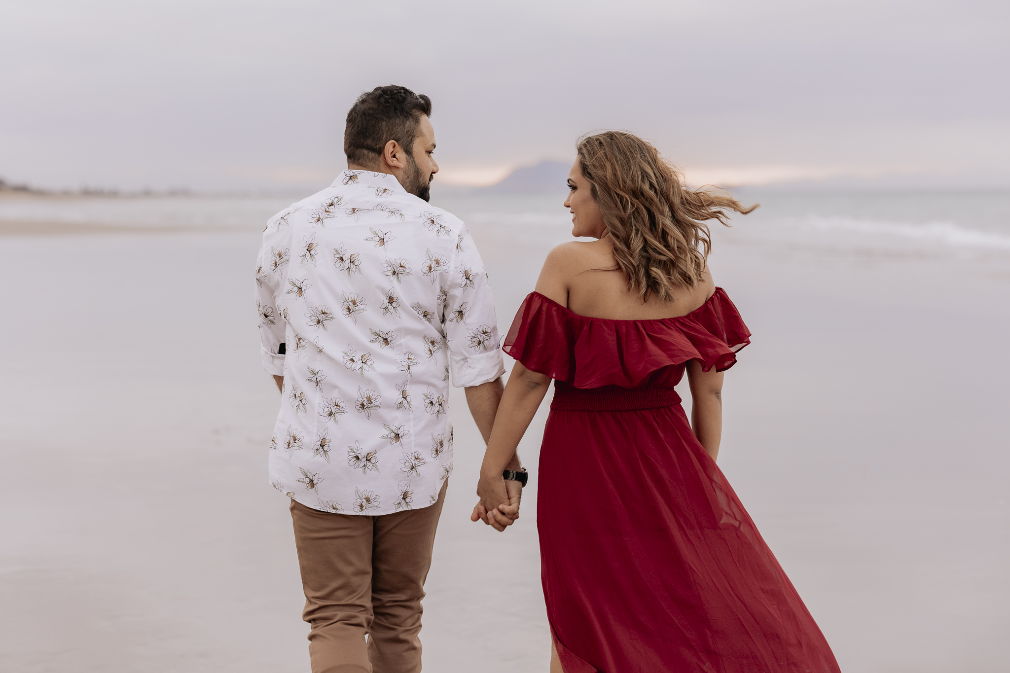 walking away holding hands at golden hour on Papamoa beach