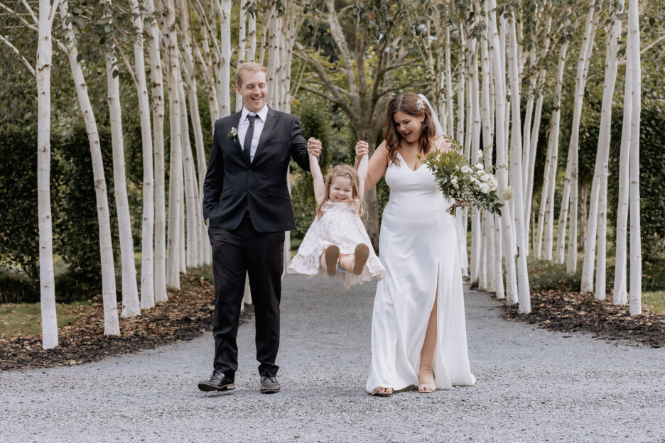 Bride and Groom play with daughter during wedding photos at Tree Church gardens