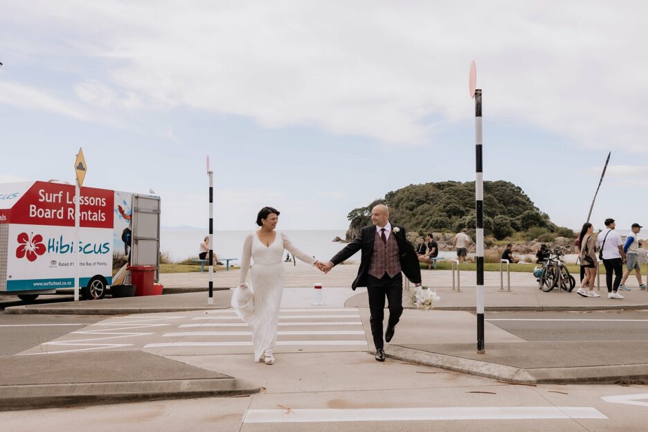 walking across crossing holding hands during wedding photos