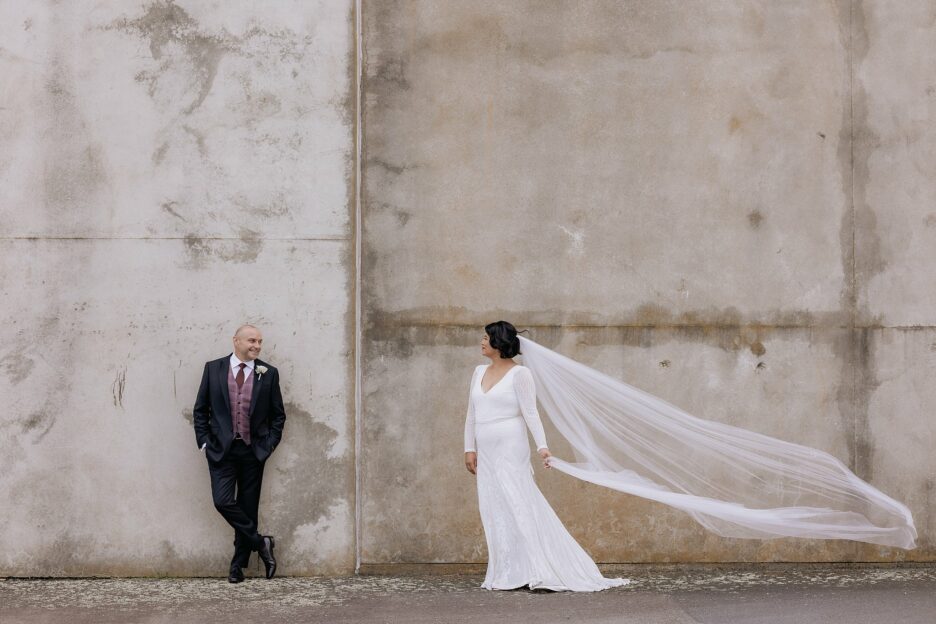 Groom looks at bride her veil flies