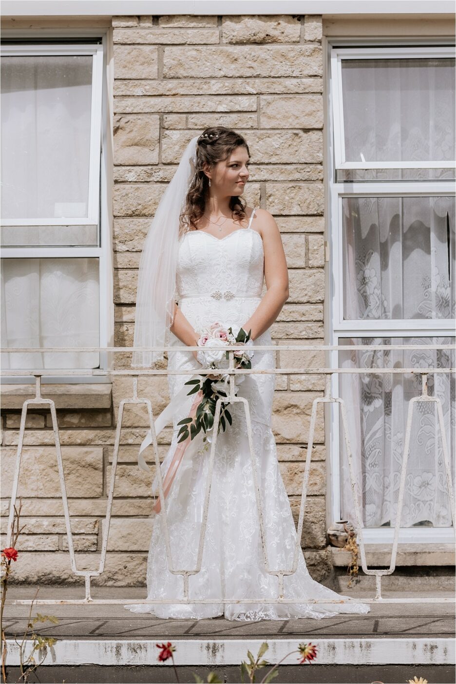 bride stands on terrace of her brick house