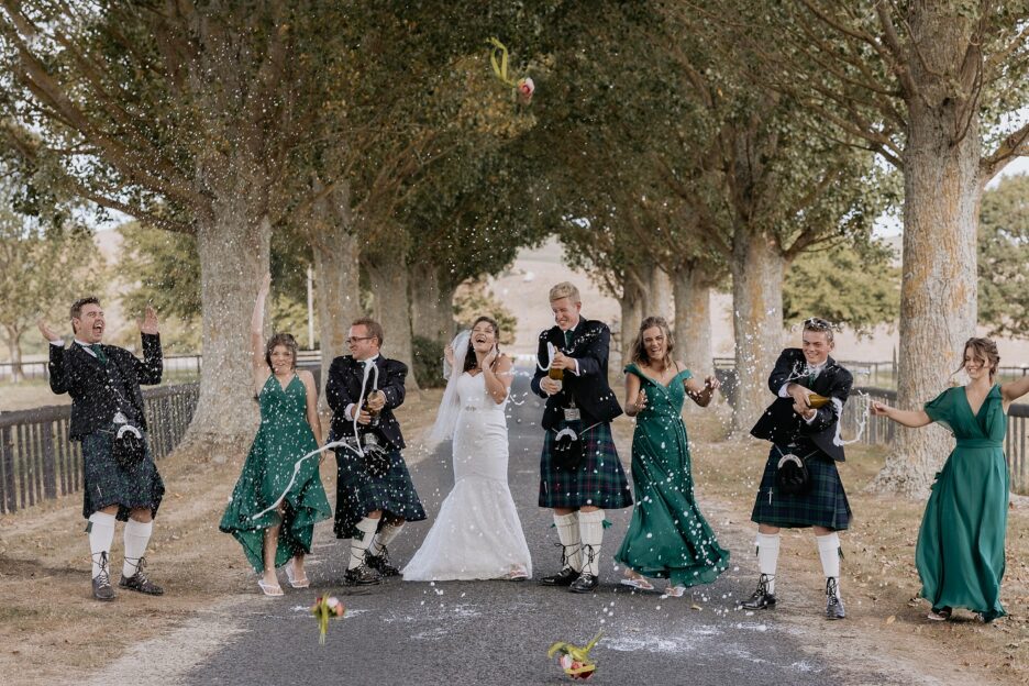 celebrating with champagne with green bridesmaids and groomsmen in kilts