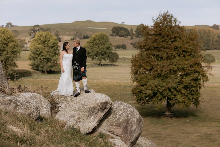 bride and groom standing on rocks high up in the Waikato Red barn