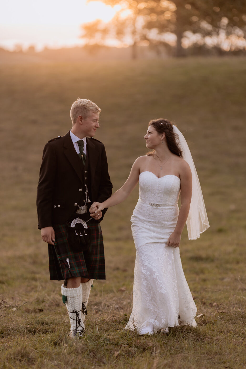 bride and groom walking in golden light in country at Red Barn wedding venue