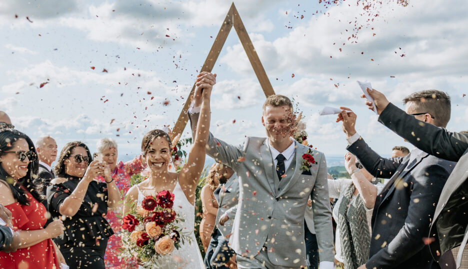 Celebration image of couple happily walking down the aisle with confetti thrown 