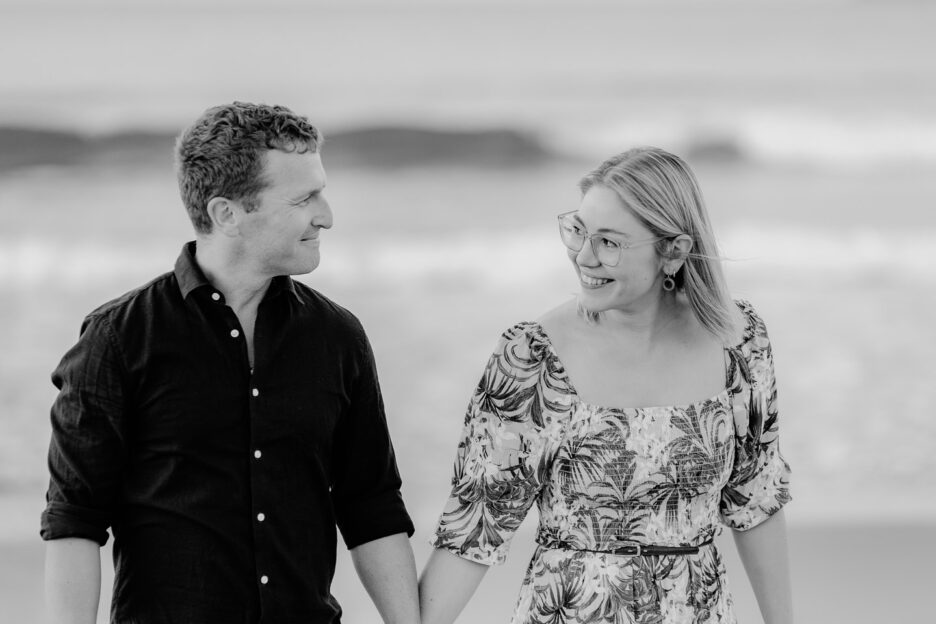 couple walking looking at each other laughing on papamoa beach