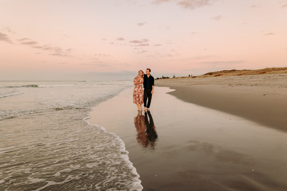 Sunset on papamoa beach Tauranga NZ walking on wet sand during engagment photo shoot