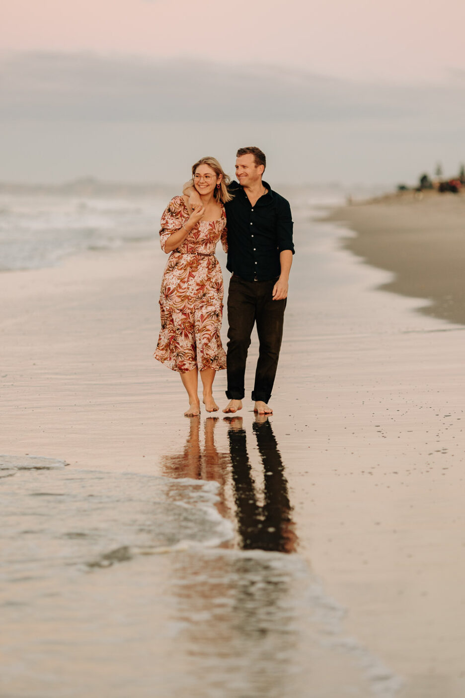 arms around each other walking on beach at sunset