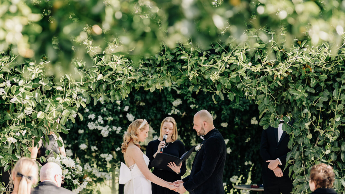 bride and groom in glass house getting married at Black walnut glass house surrounded by greenery