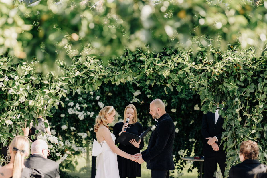 bride and groom in glass house getting married at Black walnut glass house surrounded by greenery