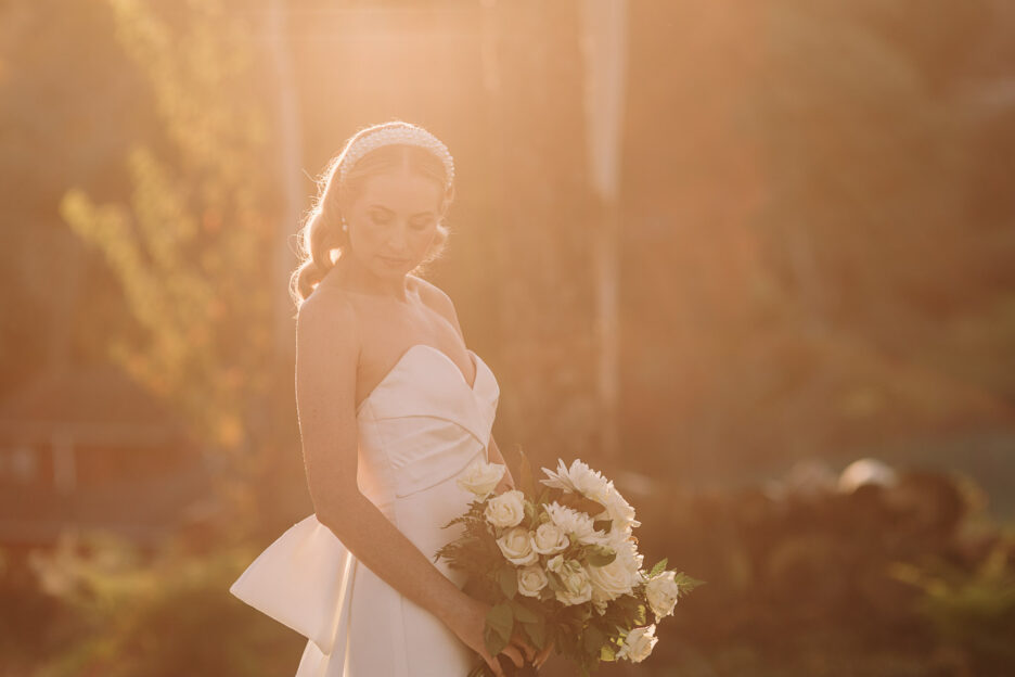 golden light of bride looking down holding flowers