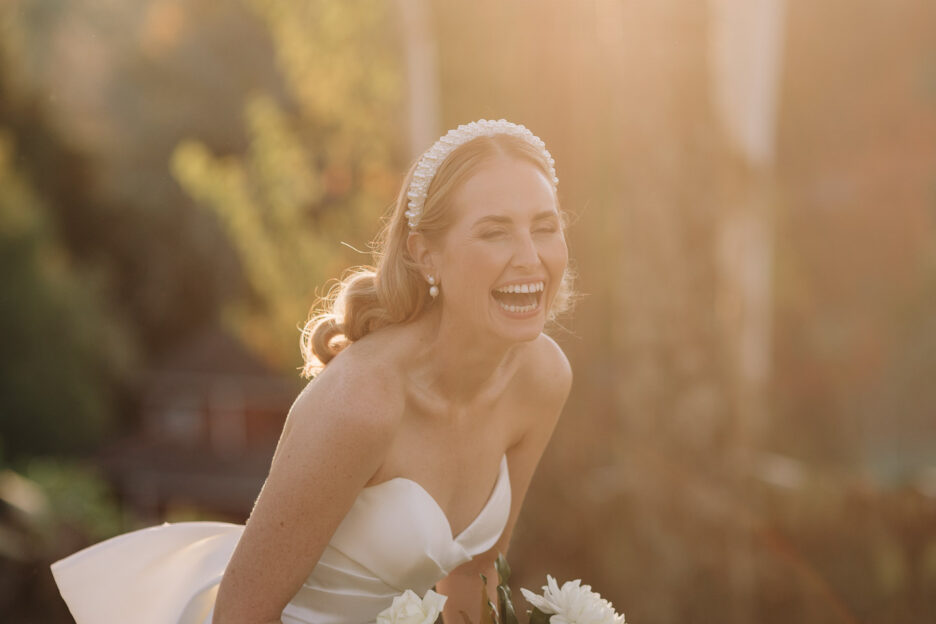 bride laughing in golden light under trees